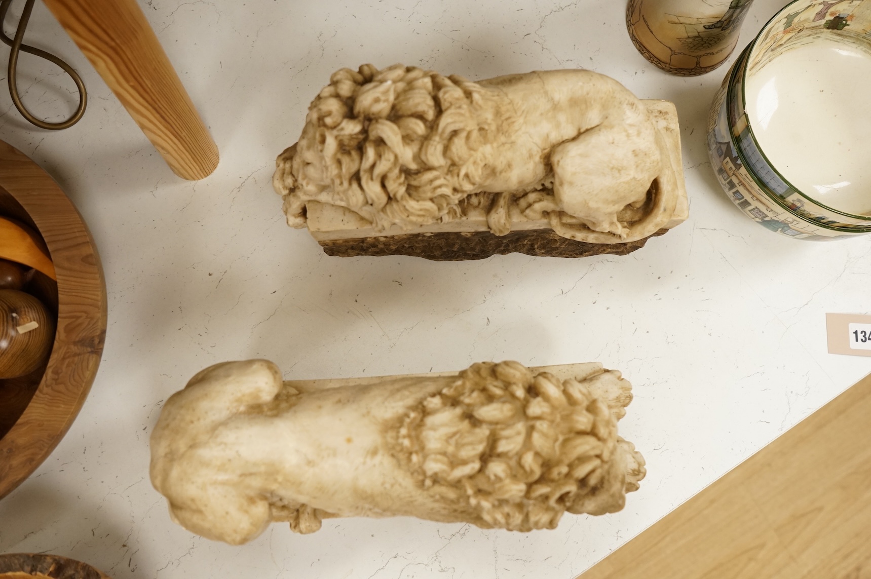 A pair of 20th century faux marble models of recumbent lions, 31cm